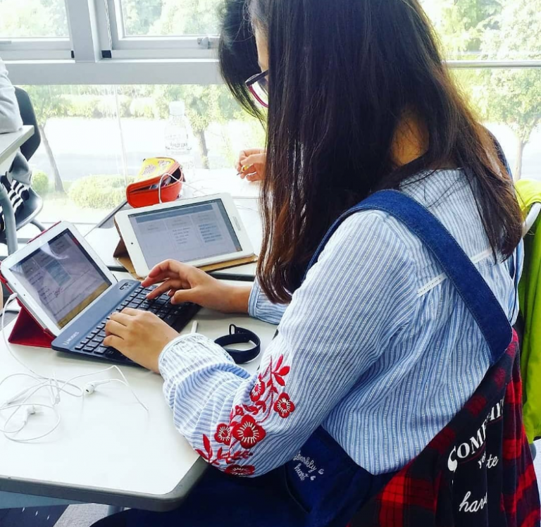 female Korean hagwon student typing on a portable keyboard attached to a tablet in class