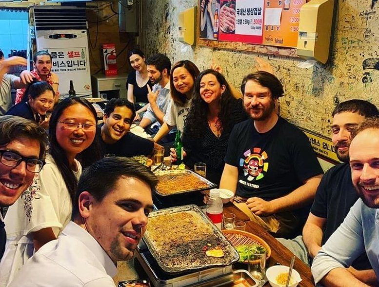 a group of smiling English teachers sitting at a large table at a restaurant in Korea