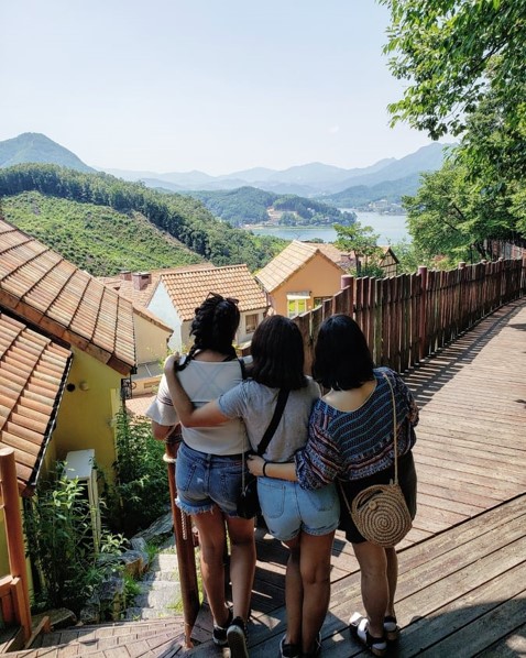 Three women overlooking a traditional Korean village