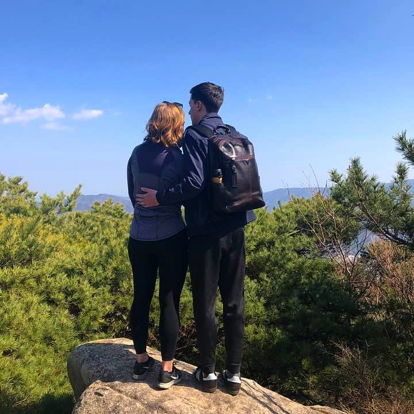 a couple looking off into the view on top of a mountain trail in korea