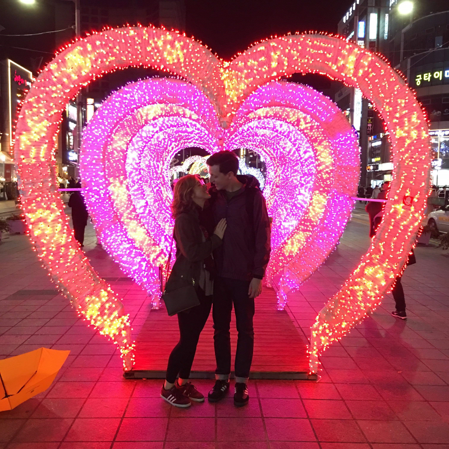 Couple posing in front of a lit heart in Korea