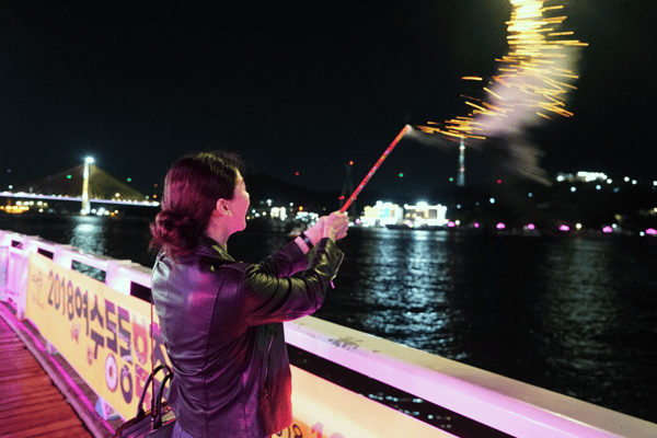 woman holding a firework sparkler by the river
