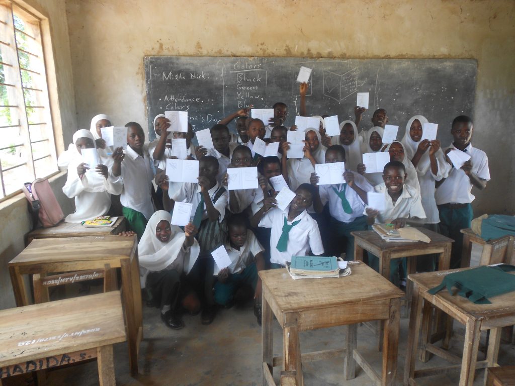 A peace Corps volunteer posing with students in a classroom in Tanzania, Africa
