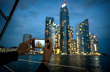 someone taking a photo night time of busan city from a boat