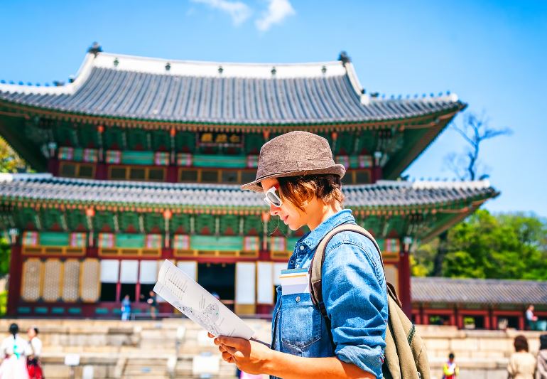 A tourist in Korea looking at a map in front of a temple palace