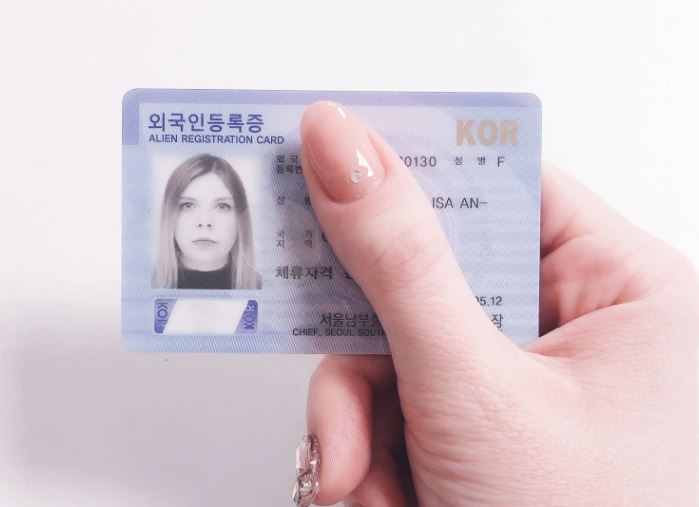 Alien Registration Card being held up by a woman's hand.