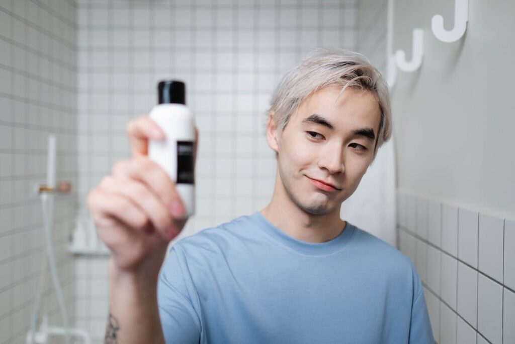 A man holding up a skincare product in his bathroom in Korea