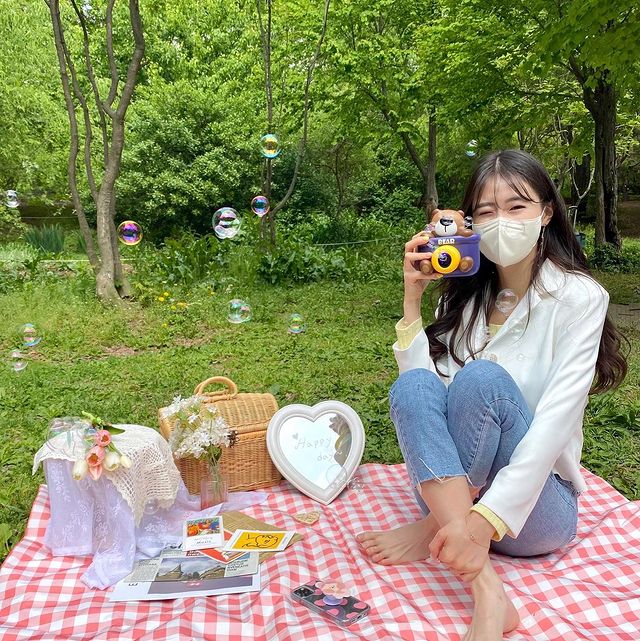 Women holding a camera having a lakeside picnic at Seoul Forest Park in Seoul Korea