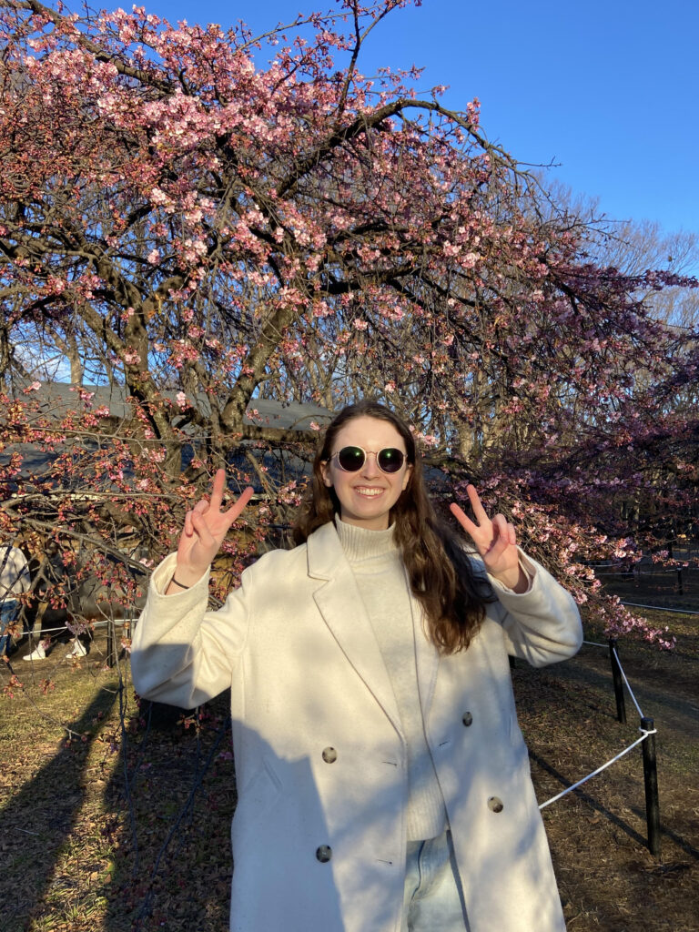 Native English Language teacher taking a picture in front of cherry blossoms in Japan